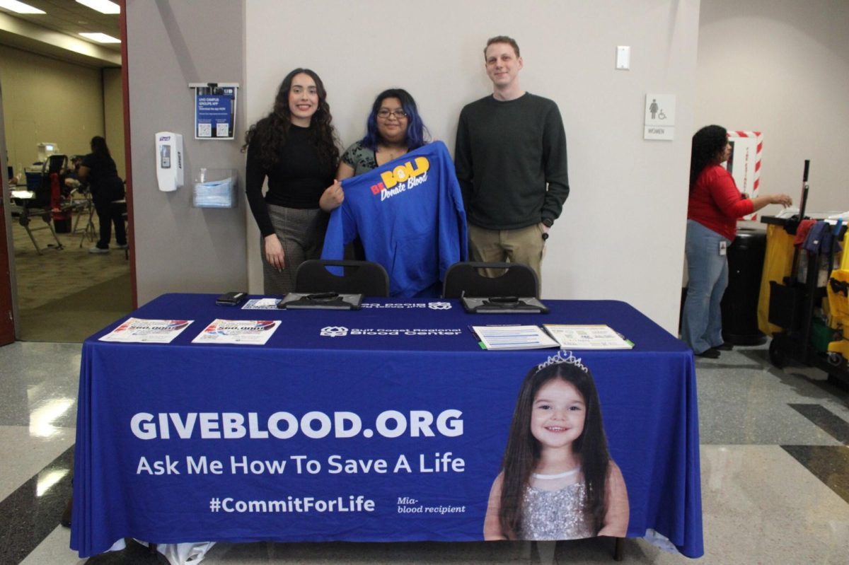 Kimberly Leyva (middle) holding a gifted sweatshirt from Gulf Coast Regional Blood Center with Stephanie Cabrera (left) and Jacob Sherman (right).