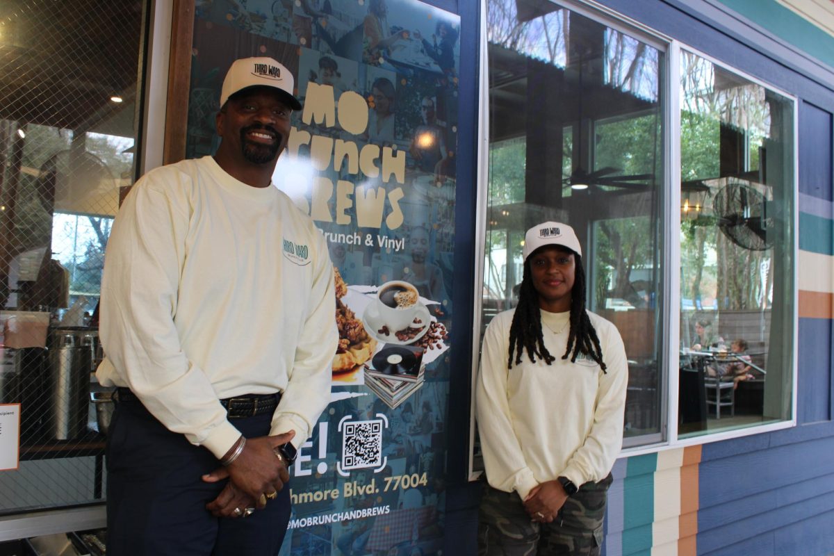 Courtney Lindsay (left) and Chasitie Lindsay (right) pose beside on of their promotional posters wearing matching Mo' Brunch & Brews attire.