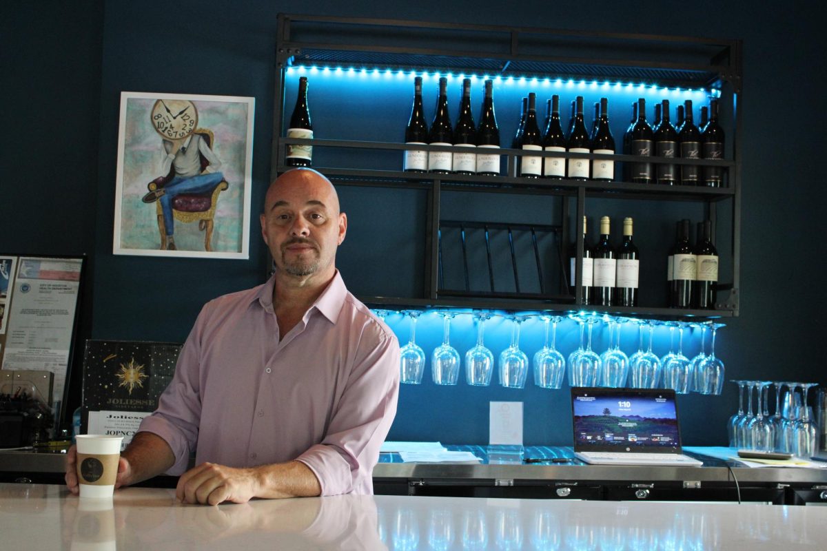 The owner, Andy Adams, pictured at the bar and in front of wine selection available at Caffvino. 
